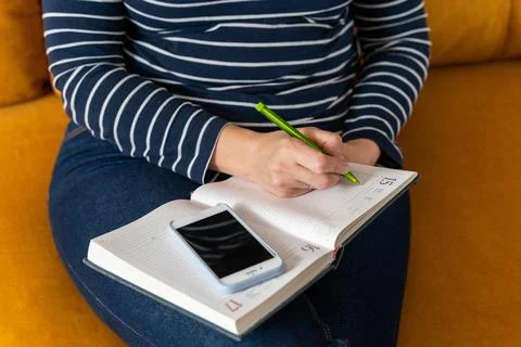 Woman makes notes in a notebook while working with a smartphone Stock Photos