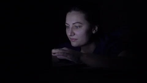 A woman makes an online purchase using a mobile computer while lying on a bed at Video stock 100723192