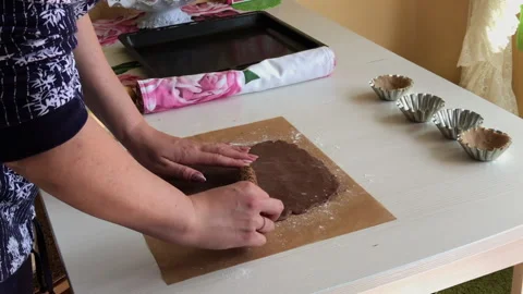 A woman makes a pattern on a rolled out dough. Using a rolling pin with a pat Stock Footage 197525628