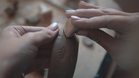 A woman makes patterns on a clay plate with a stamp. potter's hands close-up Stock Footage 89980948