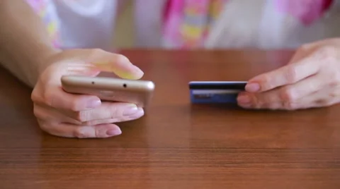 Woman makes a purchase using a smartphone and a bank card. Stock Footage
