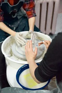 Woman making ceramic pottery, four hands close-up, focus on potters, palms with Stock Photos