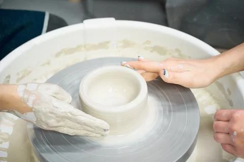 Woman making ceramic pottery, four hands close-up, focus on potters, palms with Foto stock