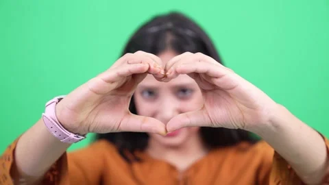Woman making heart sign using hands on chroma green studio background. 스톡 동영상 201511925