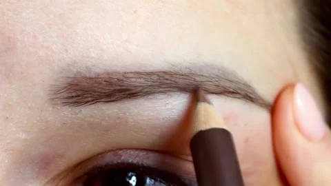 Woman making up her eyebrows with the help of brown brow pencil Stock Footage 226129057
