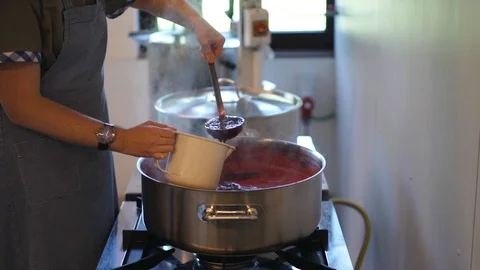 Woman making large quantity of fresh fruit jam on stove Stock Footage 128398124