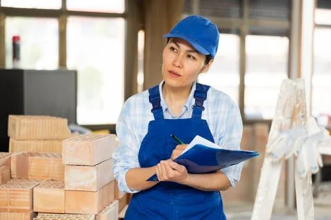 Woman making notes on indoor construction site Stock Photos
