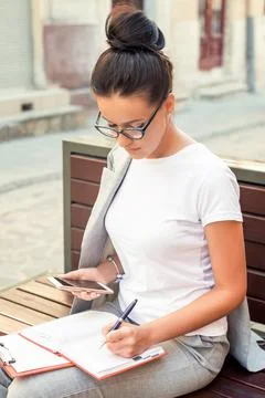 Woman is making notes in notebook. Stock Photos