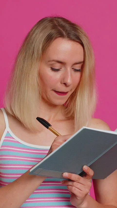 Woman making notes writing down thoughts with pen into notepad notebook diary to Stock Footage 316248124