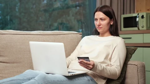 Woman making online payment using laptop and credit card on sofa Stock Footage 303499268