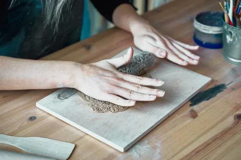 Woman making pattern on ceramic plate, hands close-up, focus on palms Stock Photos