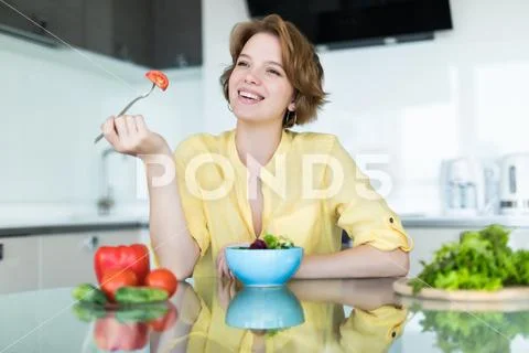 Woman making salad in kitchen. Healthy eating lifestyle concept with beautifu Stock Photos
