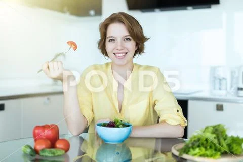 Woman making salad in kitchen. Healthy eating lifestyle concept with beautifu Stock Photos