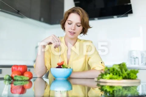 Woman making salad in kitchen. Healthy eating lifestyle concept with beautifu Stock Photos