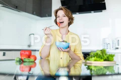Woman making salad in kitchen. Healthy eating lifestyle concept with beautifu Stock Photos