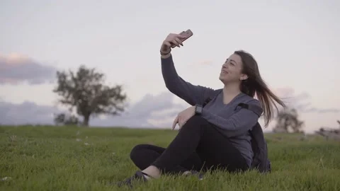 Woman making video call while sitting in park in spring Stock Footage 130905483