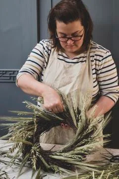 Woman making a winter wreath, adding dried grasses and seedheads and twigs with Stock Photos