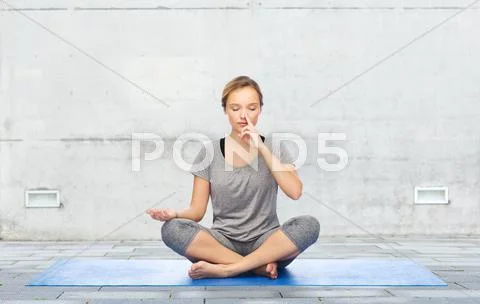 Woman making yoga meditation in lotus pose on mat Stock Photos