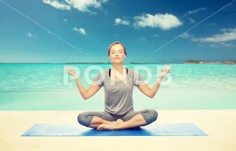Woman making yoga meditation in lotus pose on mat Stock Photos