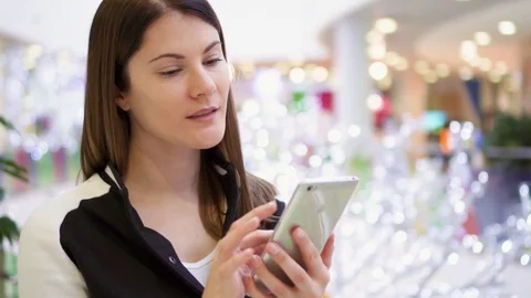 Woman in mall using mobile receiving congratulations on New Year. Christmas Stock Footage 83221158