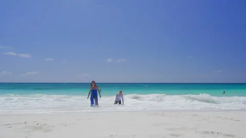 Woman, man wading through shallow ocean waves on sandy beach Stock Footage 346366277