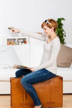 Woman with map pointing while sitting on suitcase Stock Photos
