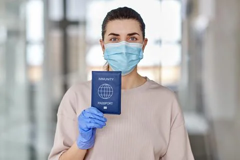 Woman in mask and gloves holding immunity passport Stock Photos