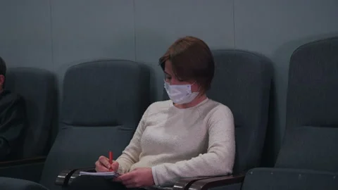 A woman in a mask makes notes in a notebook Stock Footage 150229636