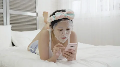Woman with mask using cellphone lying on bed Vídeo Stock 105350795