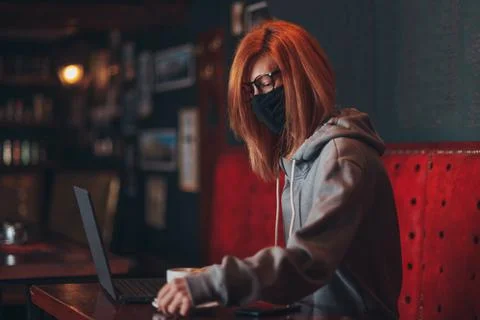 Woman with mask using a laptop in a cafe Stock Photos