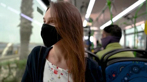 Woman in a mask while driving a bus looks out the window and smiles to camera Stock Footage 169417803