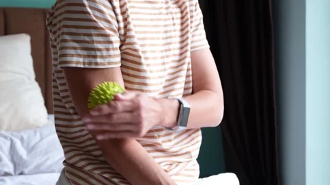 Woman massaging her biceps with a trigger point ball for pain relief Stock Footage 344465593