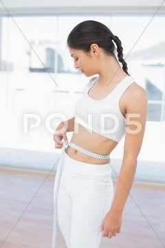 Woman measuring waist in fitness studio Stock Photos