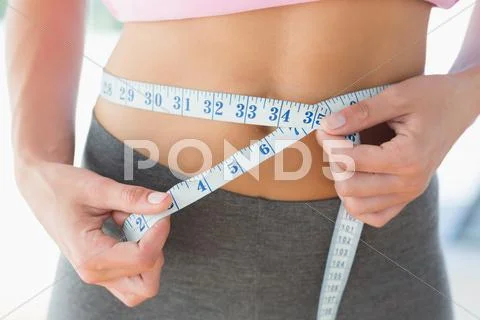 Woman measuring waist in fitness studio Stock Photos