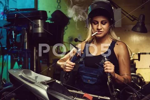 Woman mechanic working in a motorcycle workshop Stock Photos