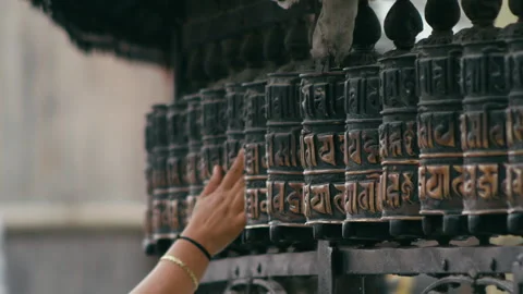 Woman meditates while turning prayer wheels in peaceful outdoor setting Stock Footage 321378417