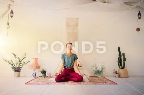 Woman meditating in lotus pose at yoga studio Stock Photos