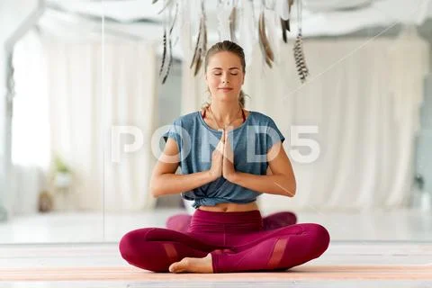 Woman meditating in lotus pose at yoga studio Stock Photos