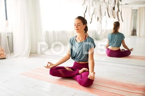 Woman meditating in lotus pose at yoga studio Stock Photos