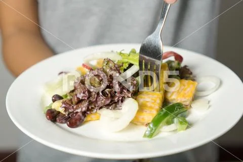Woman mixing, cooking fresh salad and vegetable for making salad. Stock Photos