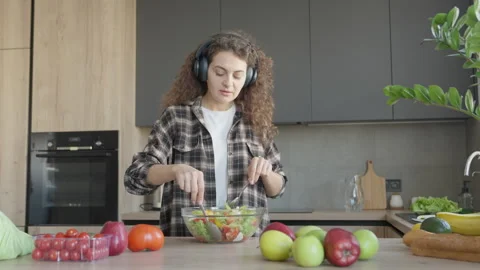 Woman Mixing Fresh Vegetable Salad While Listening To Music Stock Footage 344698341