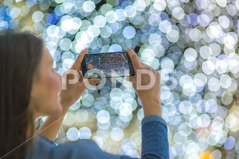 The woman with mobile camera shot bright garland Stock Photos