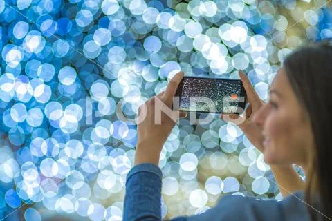 The woman with mobile camera shot bright garland Stock Photos