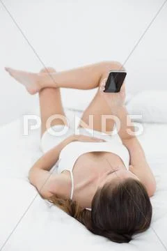 Woman with mobile phone in bed Stock Photos
