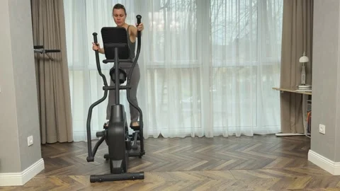 Woman moving backward on elliptical machine at home, Concept of reverse cardio Vídeos de archivo 341865902