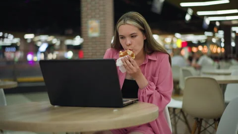 Woman Multitasking Between Work and Eating at Busy Mall Stock Footage 287731427