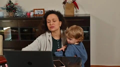 Woman multitasking while working from home with a child Stock Footage 296551566