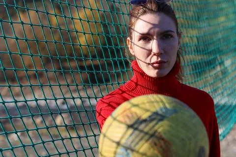 Woman with net pattern shadow holding yellow volleyball outdoors Stock Photos