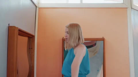 Woman observes distorted mirror reflection. Serene indoor setting features woman Stock Footage 335299581