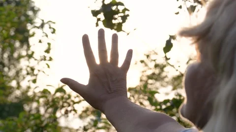 Woman observing sunlight through hand at sunset Vídeo Stock 312696583